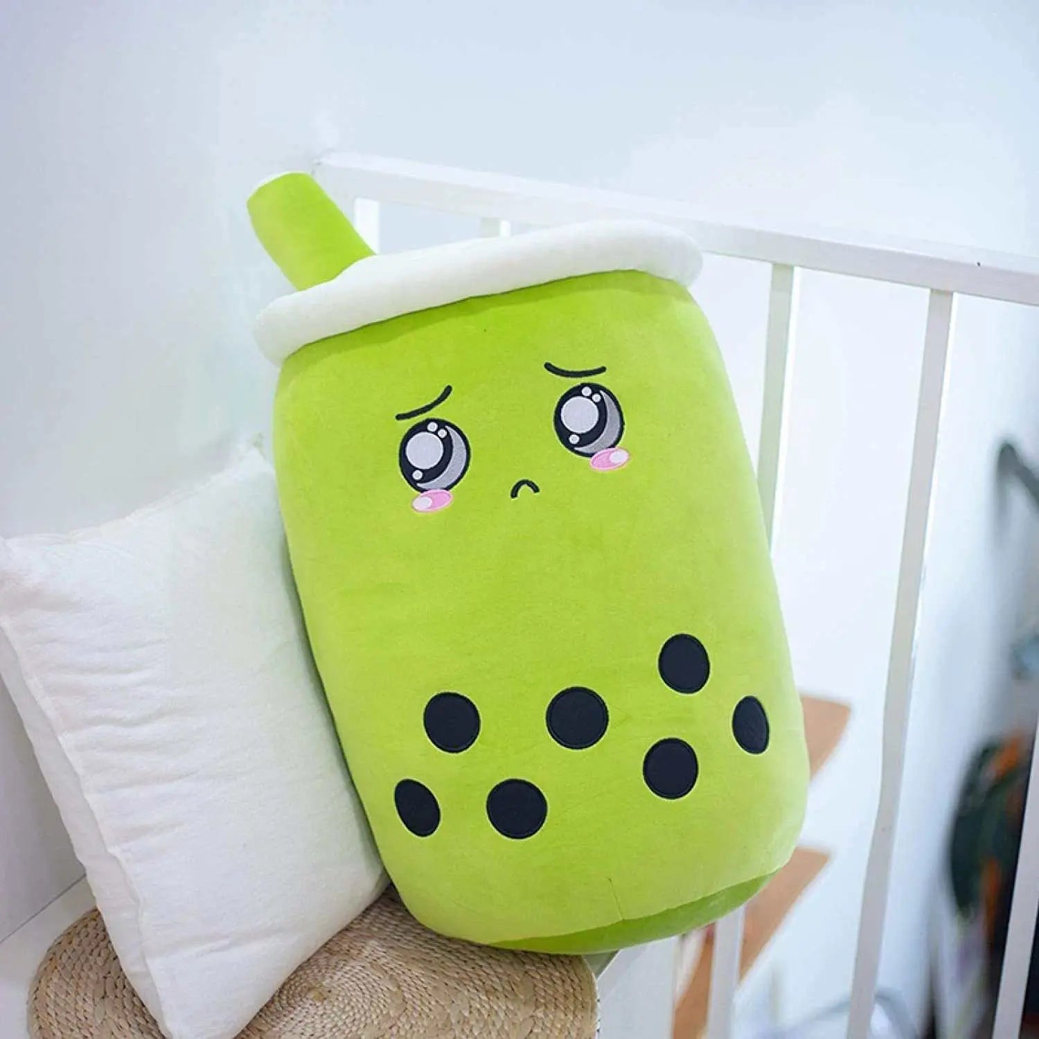 Soft green plush boba stuffed toy pillow with embroidered sad eyes and black tapioca pearls