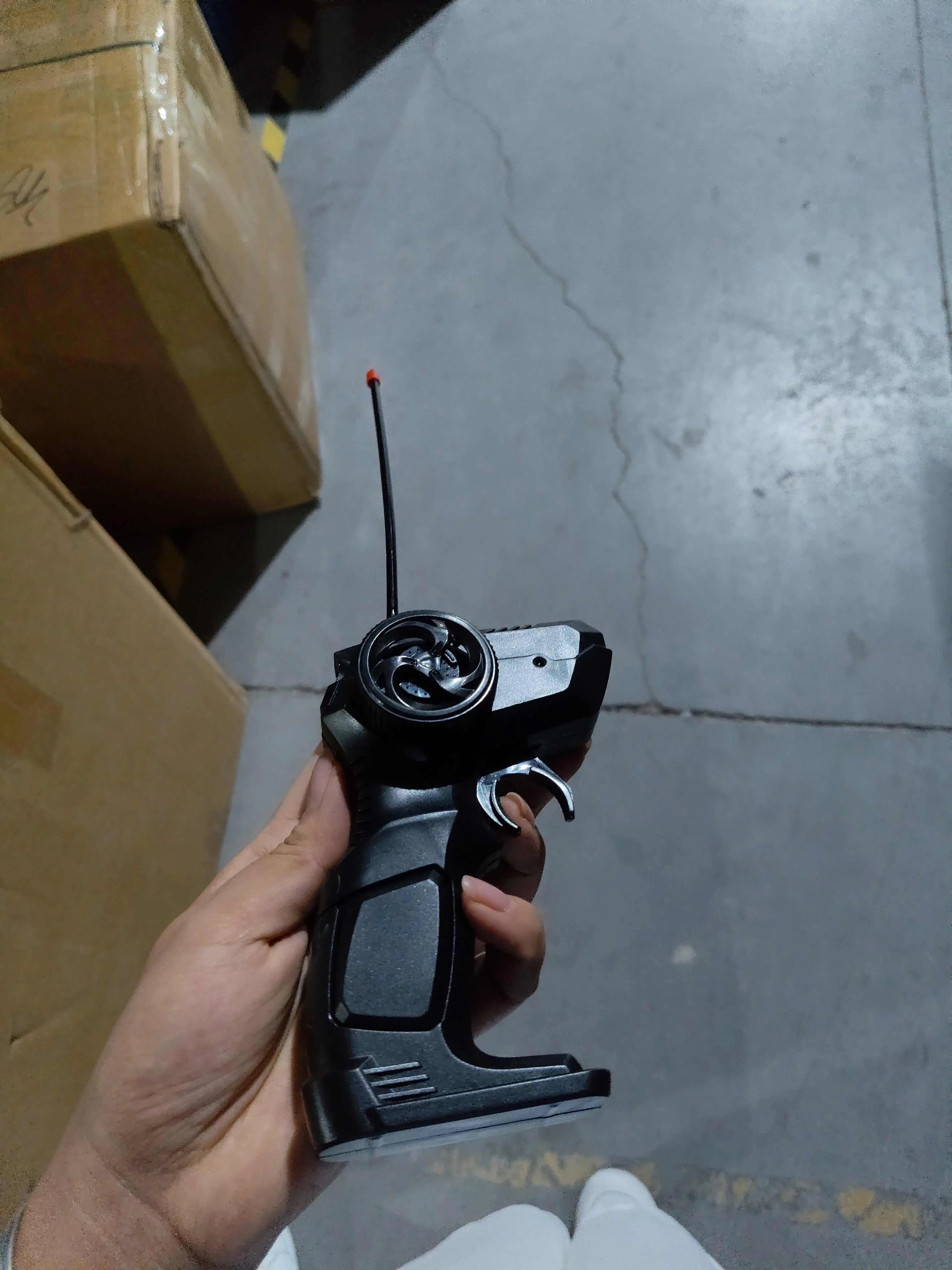 Hand holding black 2.4G remote control for 4WD RC Car on concrete floor background