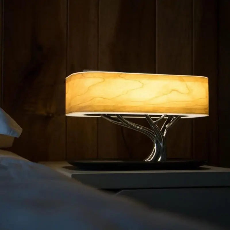 Tree of Life Table Lamp with Bluetooth speaker, wireless charging, and dimmable natural cherry wood design on bedside table