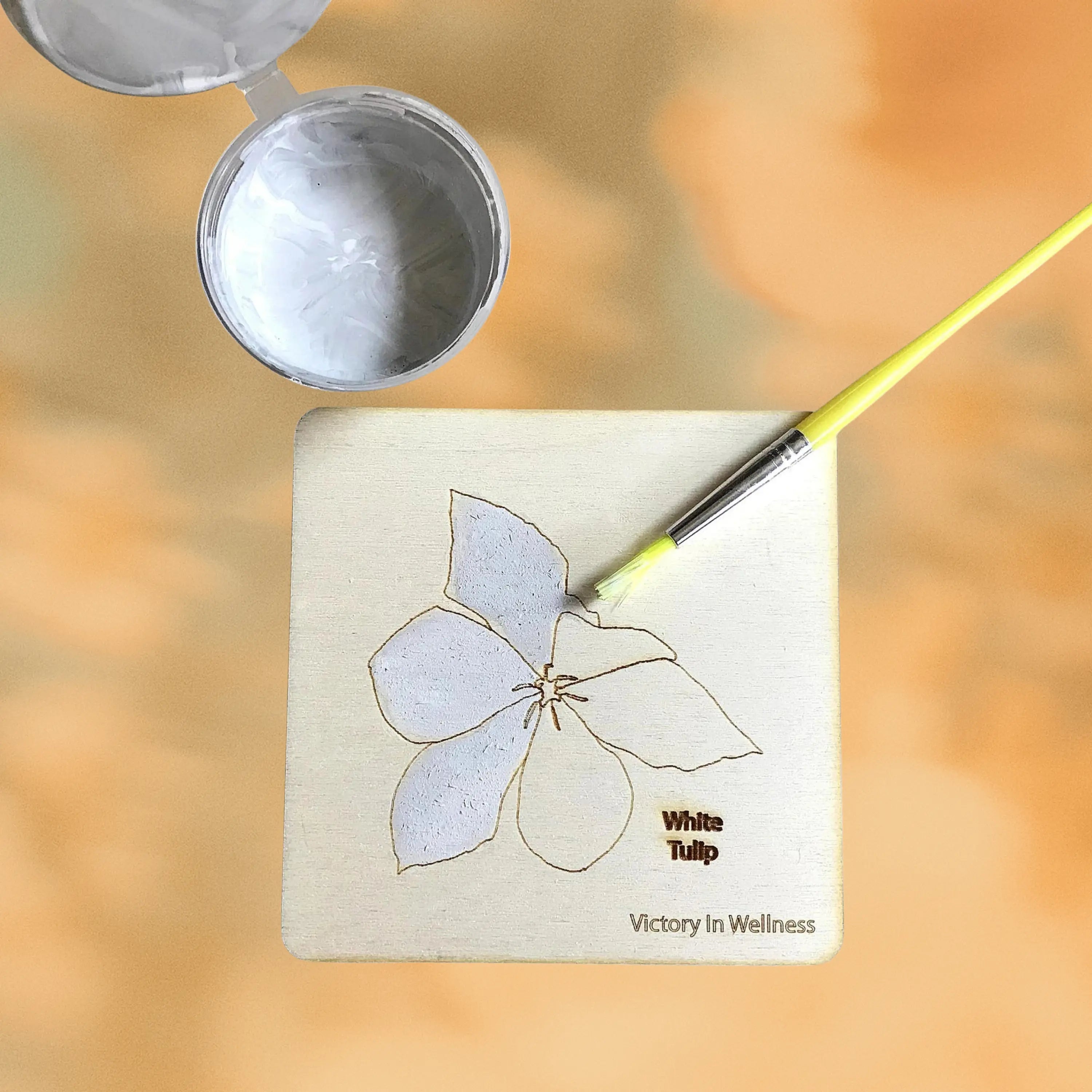botanical coasters wooden square with white tulip design being hand painted with yellow brush