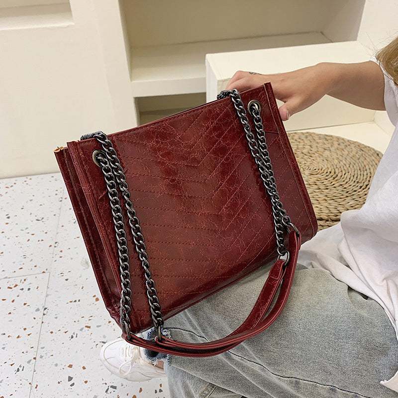 Stylish red ladies messenger bag in PU leather with chain shoulder straps and zipper closure