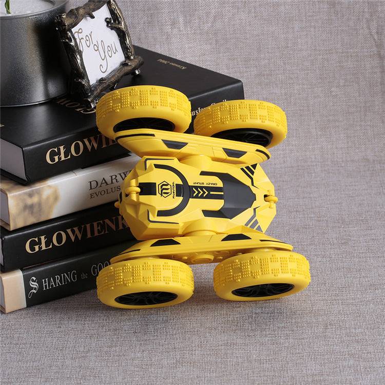 Yellow Storm Stunt RC Car performing a stunt flip on a gray fabric surface near stacked books