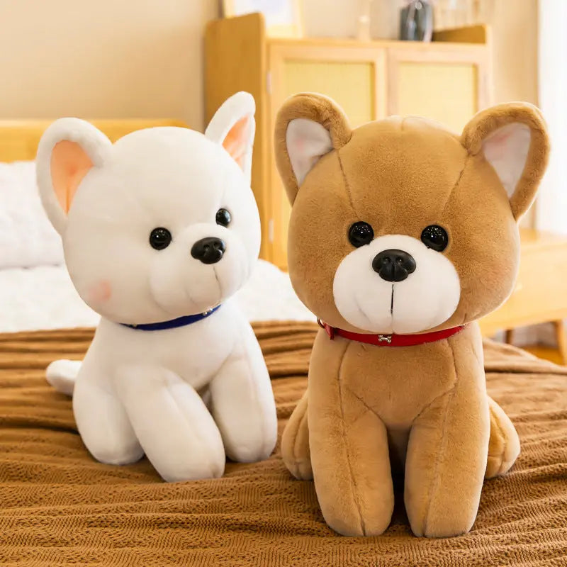 Two adorable plush puppy dolls in white and brown colors sitting on a bed, soft and huggable cartoon-style stuffed toys