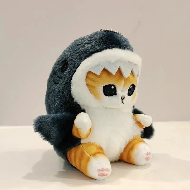 Plush toy resembling a cat in a shark costume on a neutral background