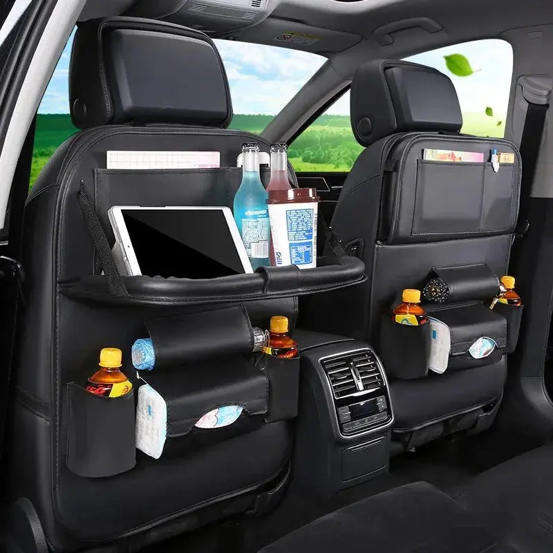 Car interior with black organizer attached to back seat holding drinks, snacks, and a tablet.