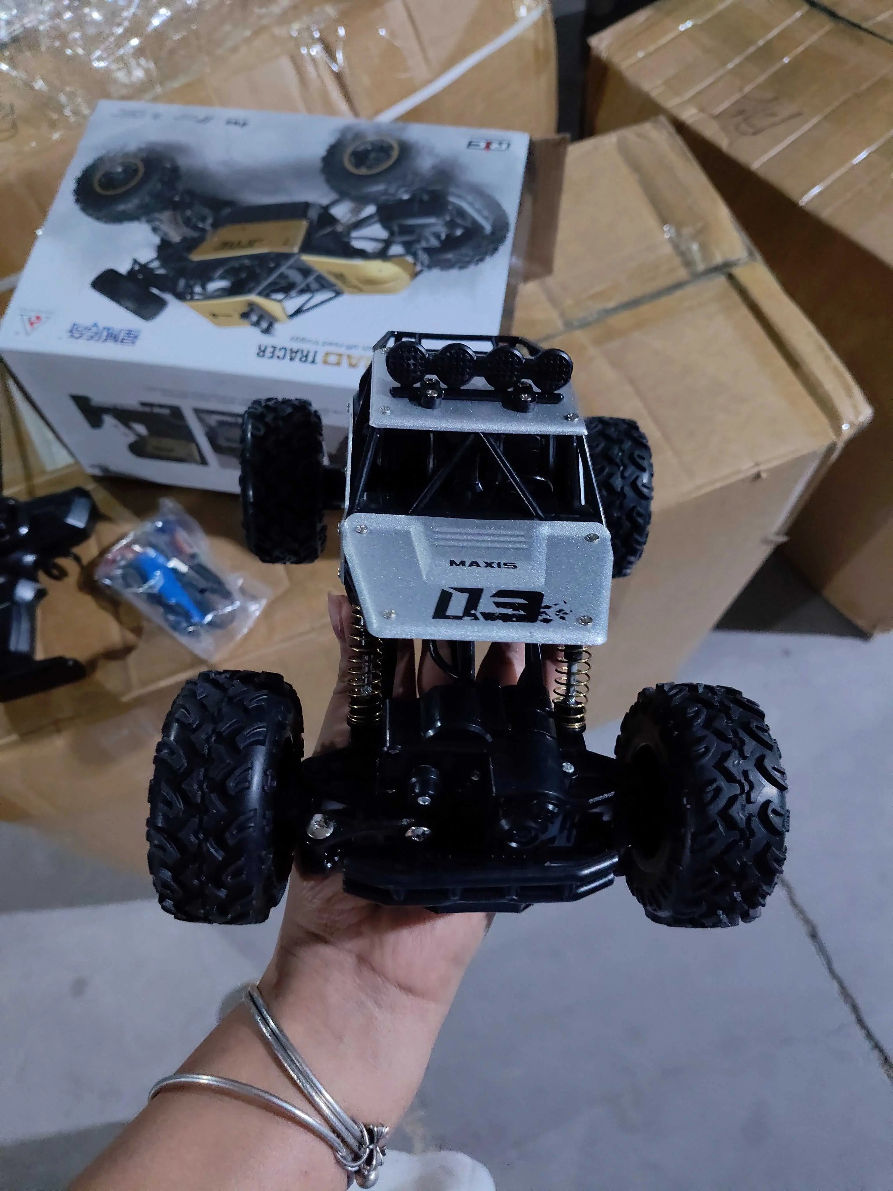 Handheld 4WD RC off-road buggy truck with large tires and roof lights, shown with packaging and accessories.
