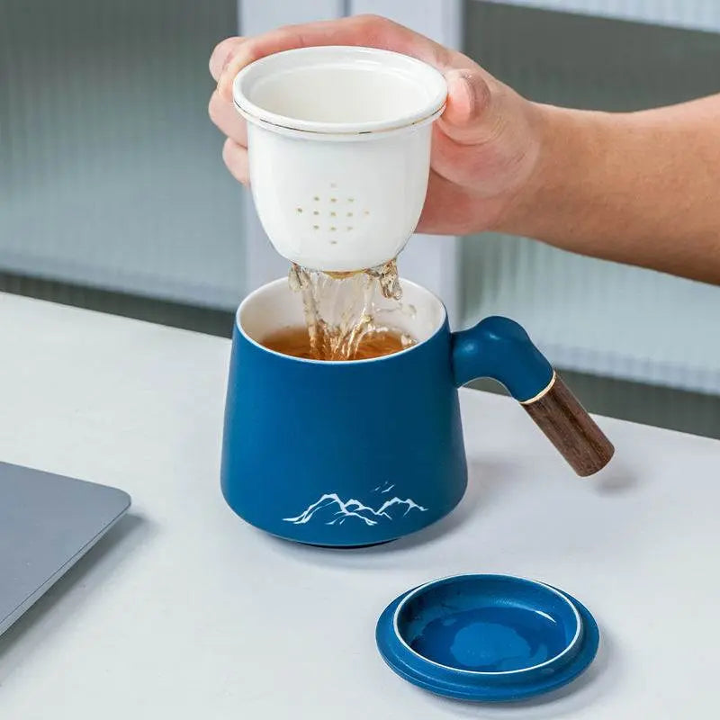 Blue ceramic mug with infuser being filled with tea, part of Massage Gun Gift Box business gift set