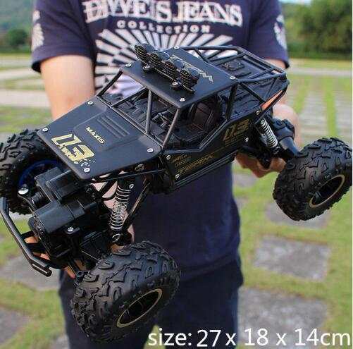 Black 4WD RC off-road climbing truck with rugged tires held by person outdoors, size 27x18x14cm
