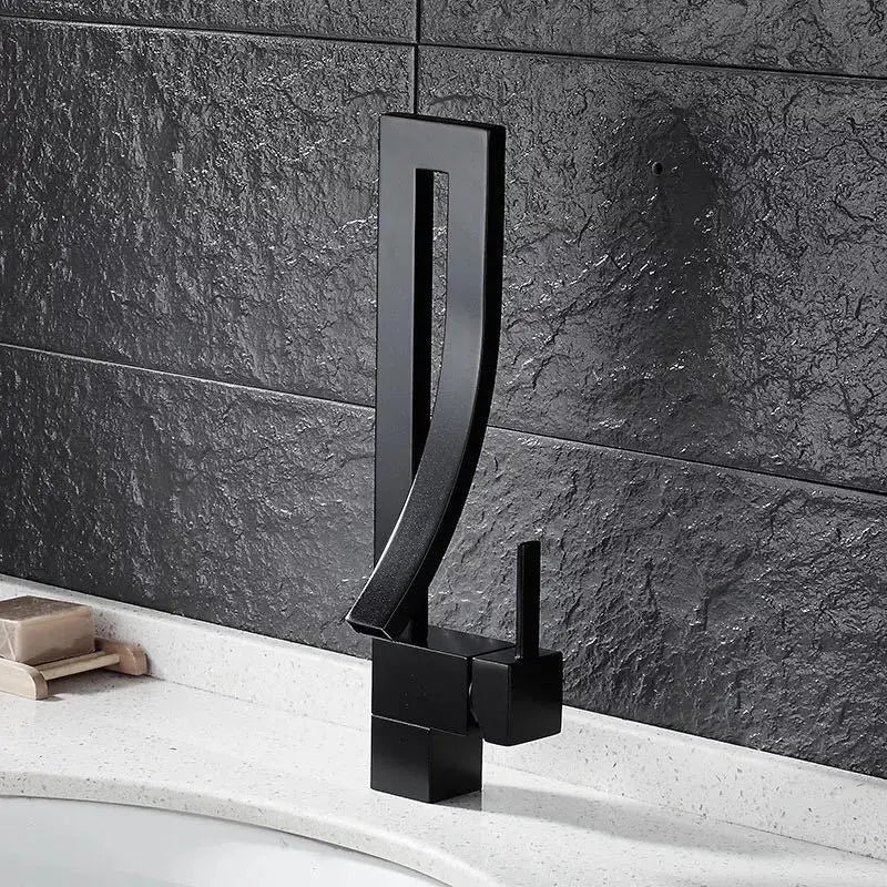 Black faucet on a bathroom sink with dark tiled wall background