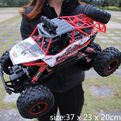 Red and black 4WD RC off-road buggy with large tires held outdoors, size 37x23x20 cm