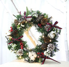 Christmas wreath hanging decoration with pinecones, red berries, cotton accents, and ribbon bows on green garland with lights