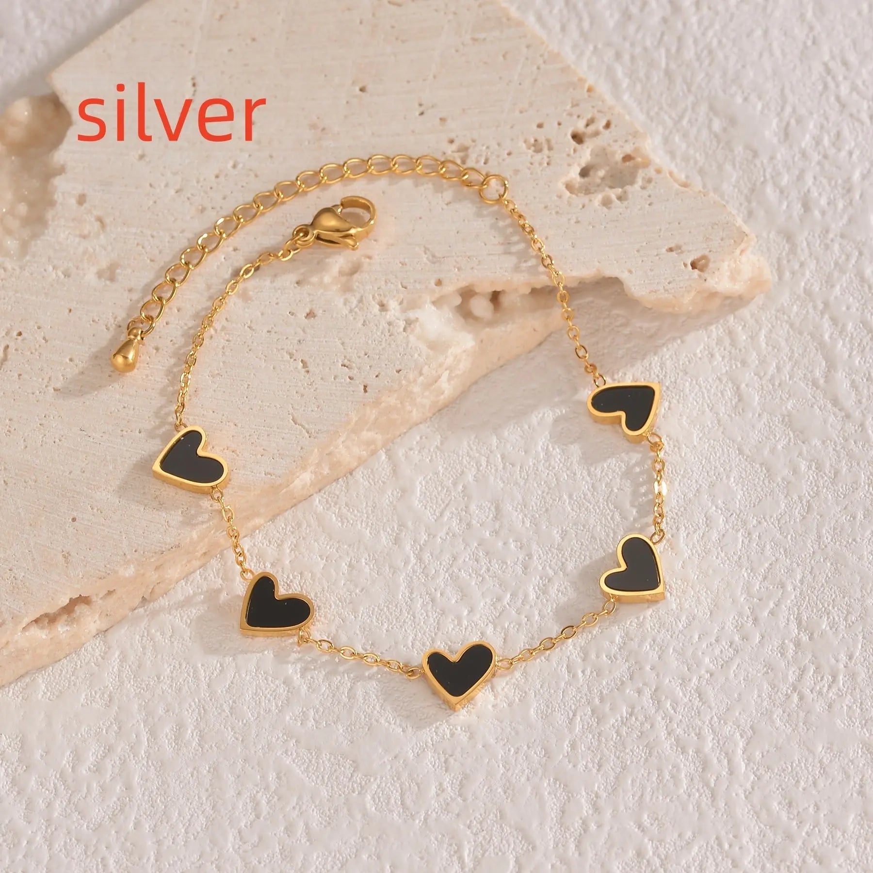 Gold colored fashion bracelet with black love heart charms on adjustable chain