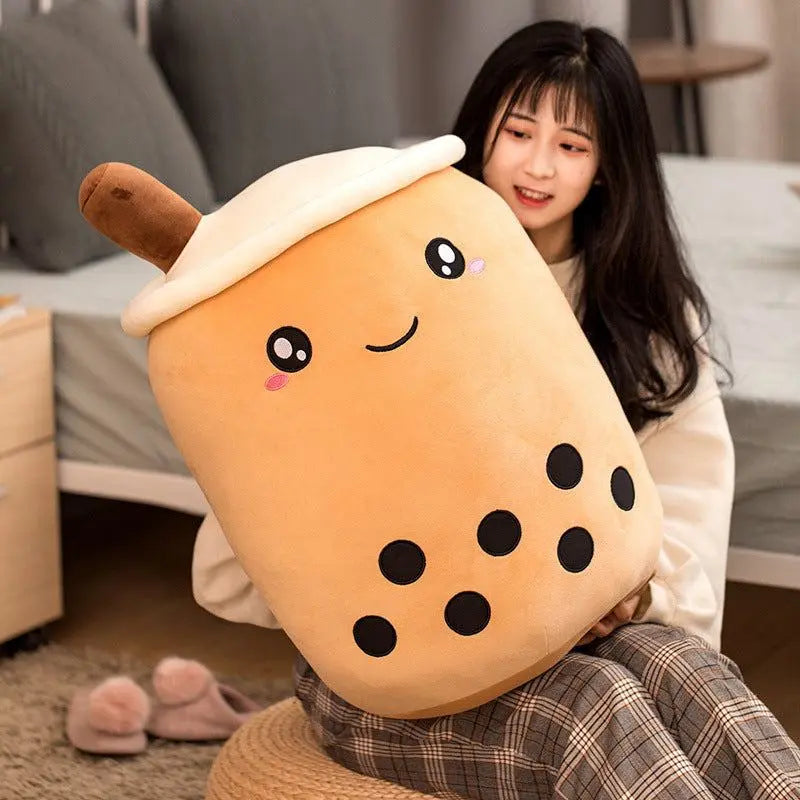 Young woman holding large plush boba stuffed toy pillow with smiling face and black tapioca pearls design