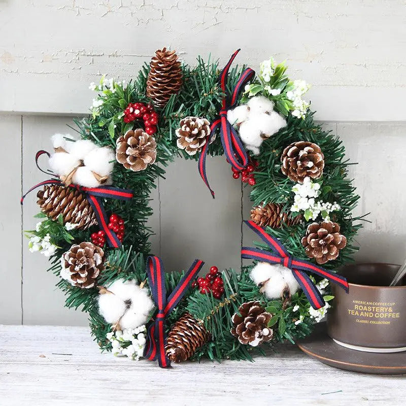 Handcrafted Christmas wreath hanging decoration with pine cones, cotton accents, red berries, and ribbon bows in green PVC garland.