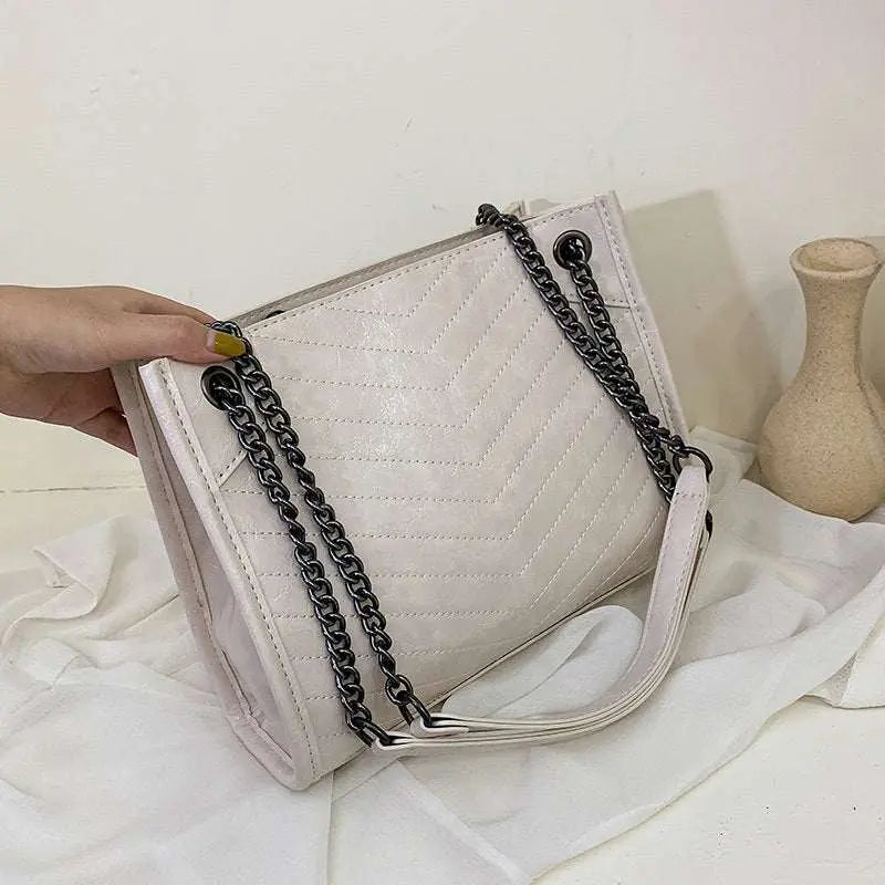 Stylish ladies messenger bag in beige PU leather with black chain shoulder strap and zipper closure