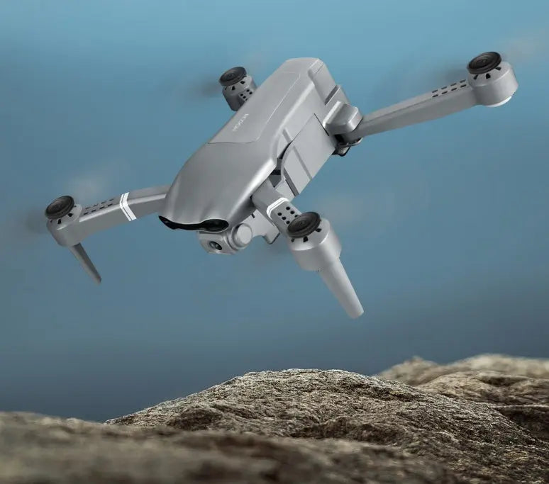 Compact 4K folding drone with GPS positioning and dual HD cameras flying over rocky terrain
