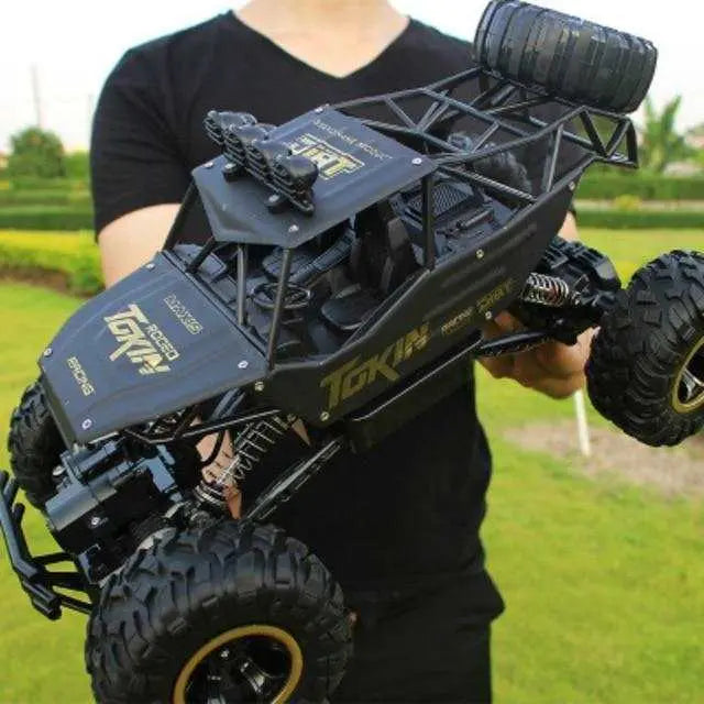 Black 4WD RC Car off-road climbing truck held in hands with large tires and metal frame