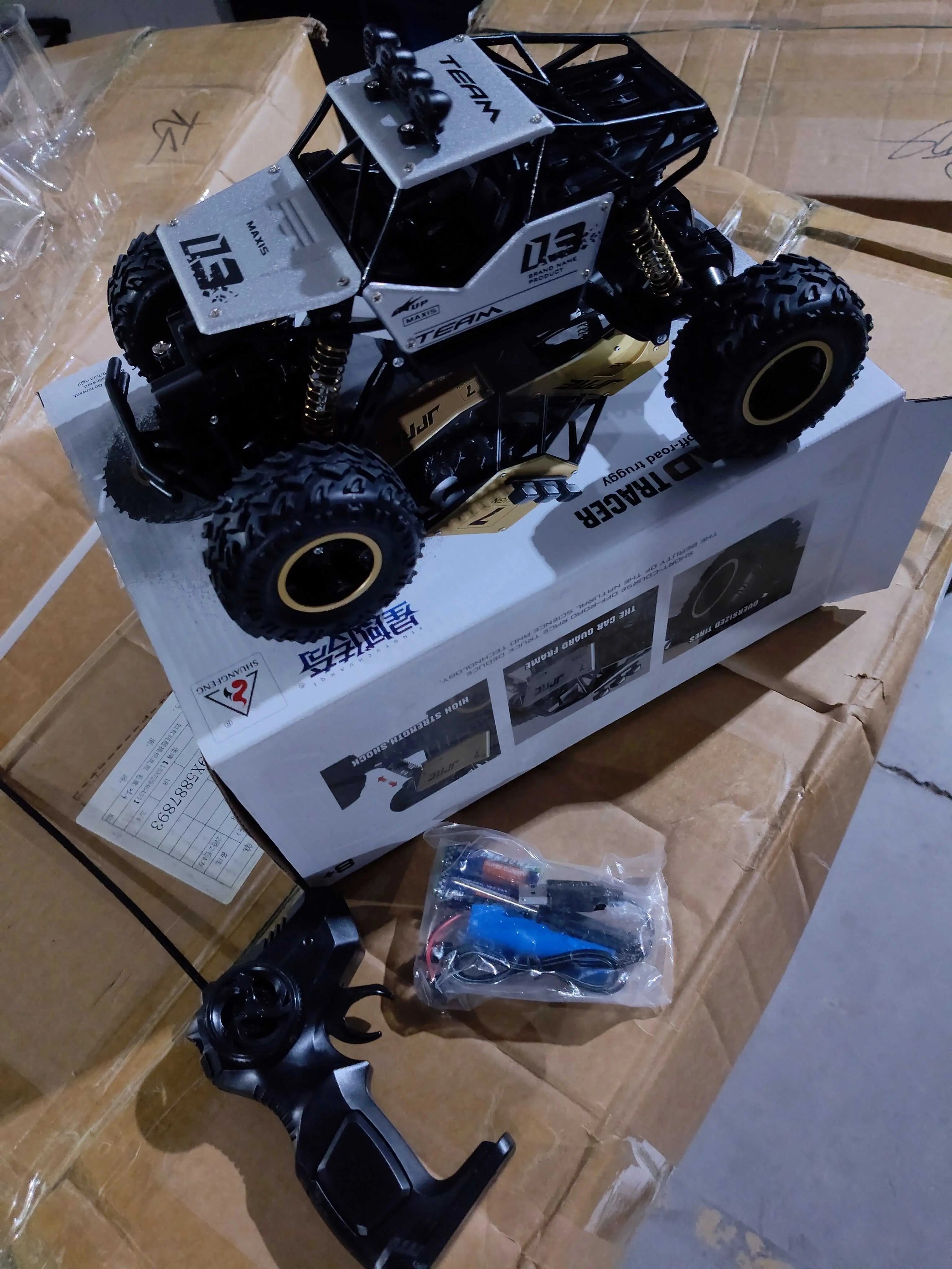 Black and white 4WD RC car on box with remote and accessories on cardboard surface