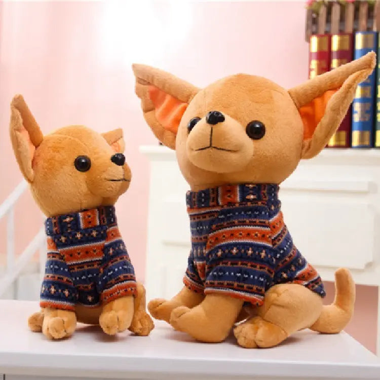 Two adorable plush dog dolls wearing cozy patterned sweaters sitting on a white surface