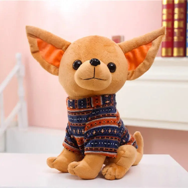 Adorable plush dog doll toy wearing a patterned sweater sitting on a white surface in a cozy indoor setting