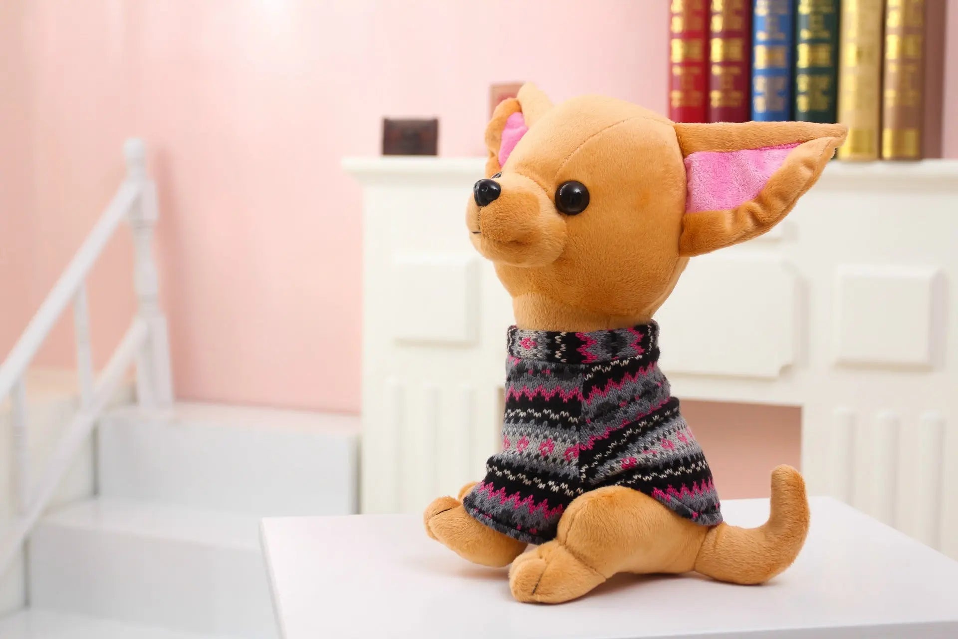 Adorable plush dog doll toy wearing a patterned sweater sitting on white surface in cozy indoor setting