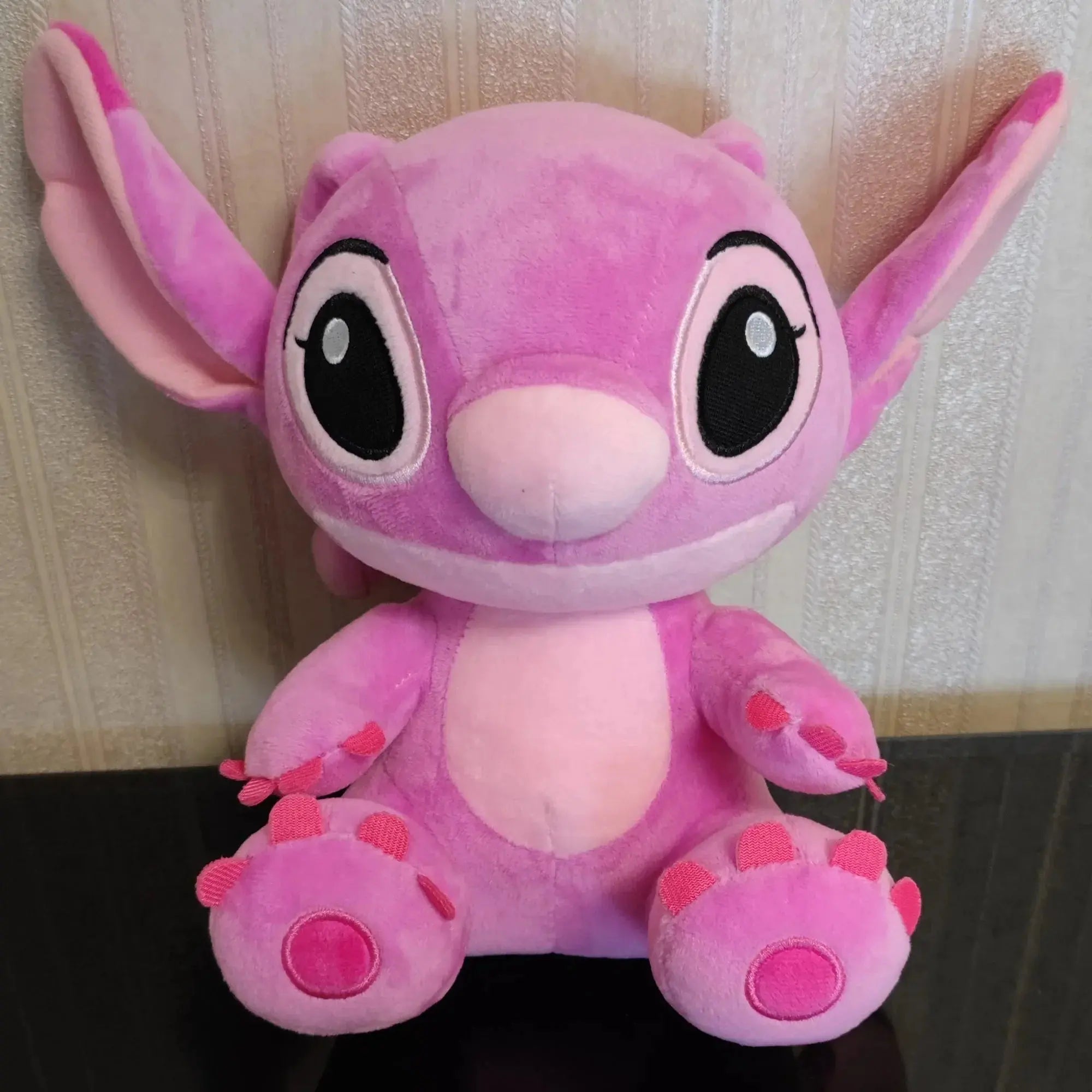 Pink plush toy with large eyes on a neutral background