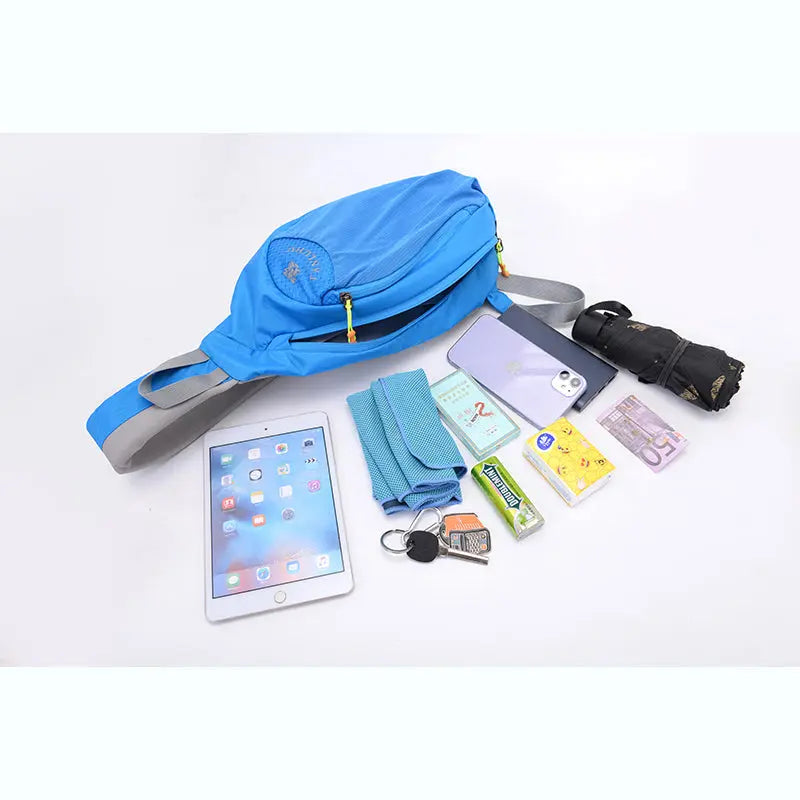Blue outdoor sling crossbody bag with essentials for hiking and daily use including tablet, phone, keys, umbrella, and toiletries