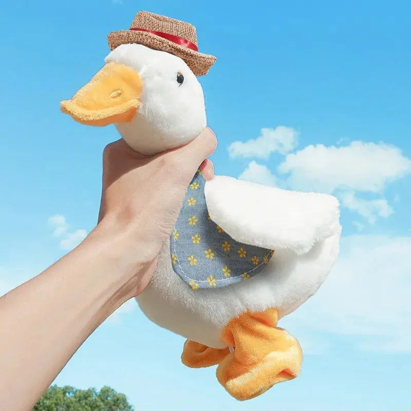 Plush duck toy with a straw hat and blue dress held against a clear blue sky.
