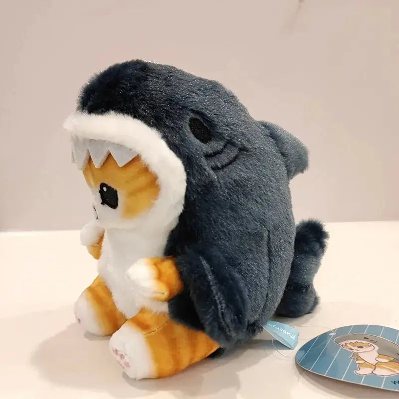 Plush toy resembling a shark with a small animal inside on a white surface.