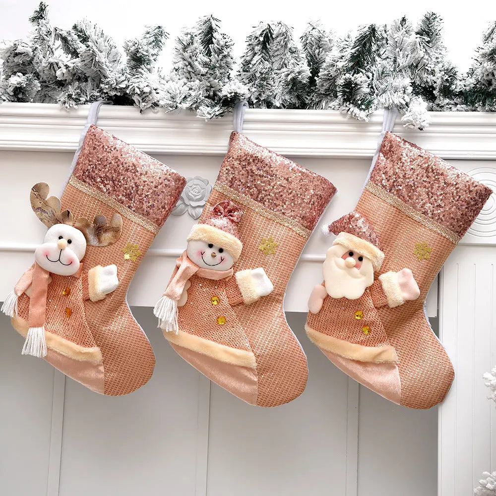 Three sequined Christmas stockings with reindeer, snowman, and Santa designs hanging by a snowy garland on a white mantelpiece