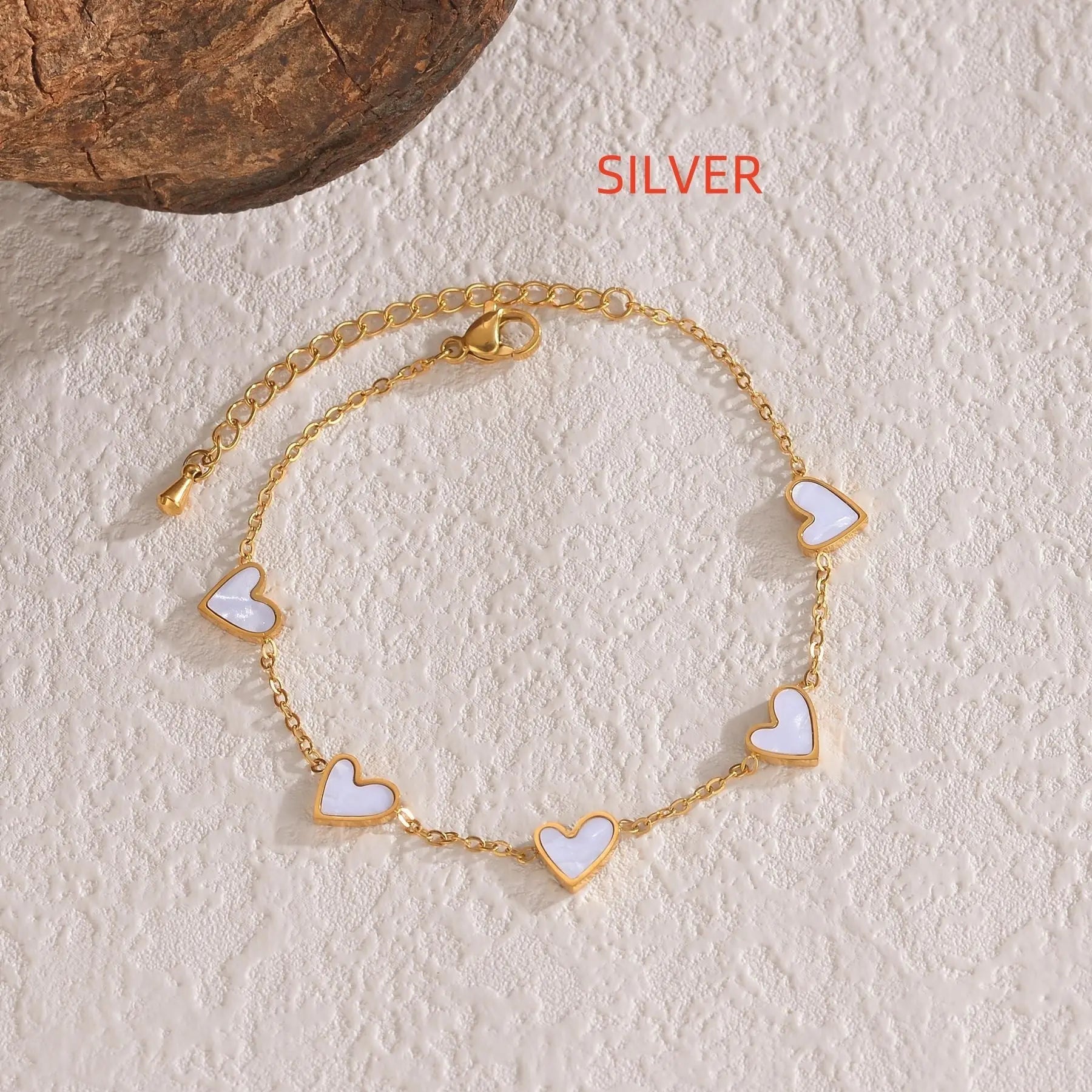 Gold colored love heart bracelet with white heart charms on adjustable chain