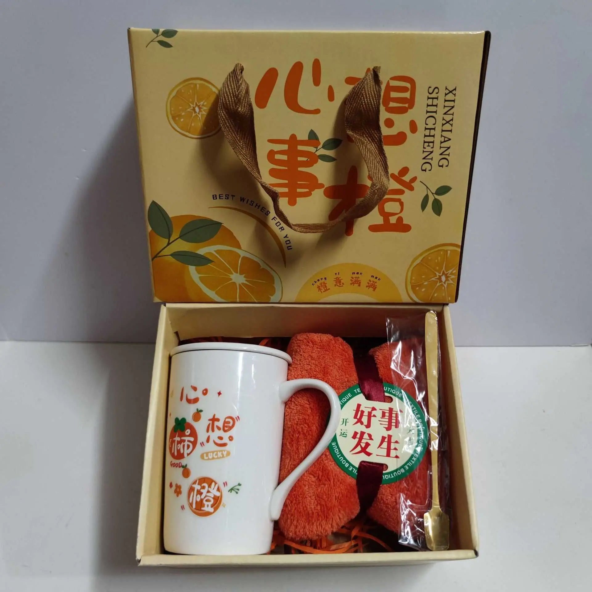 Ceramic cup gift box set with white porcelain mug, orange towel, spoon, and decorative gift packaging