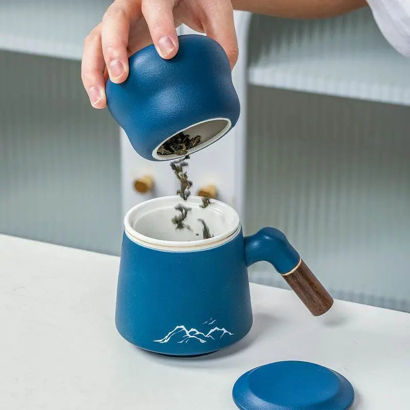 Blue ceramic mug with wooden handle being filled with tea leaves, luxury business gift set component